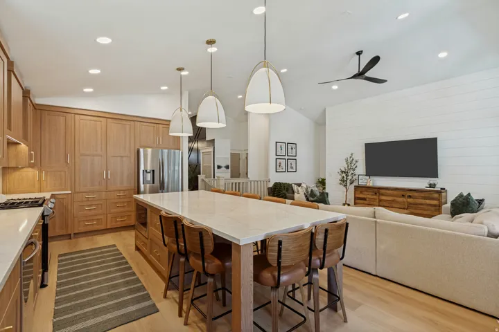 Kitchen featuring light wood cabinetry, a large center island with seating, and stainless steel appliances