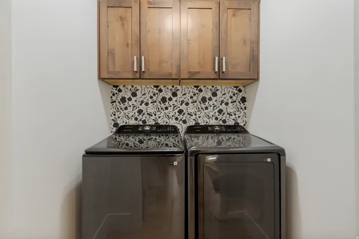 Wood-finish upper cabinetry with brushed nickel hardware and a decorative patterned backsplash