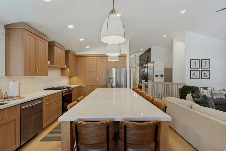 Open-concept kitchen featuring light wood cabinetry, stainless steel appliances, a gas range, and a large central island with seating