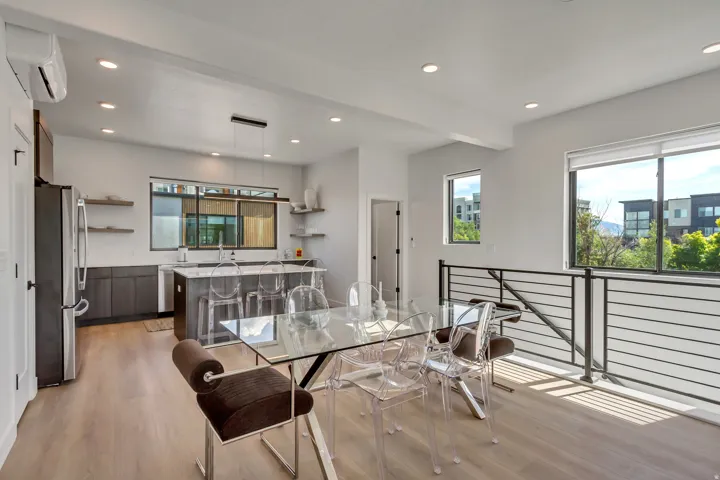 Open-concept living space with wood-finish flooring, recessed lighting, and a kitchen featuring dark wood cabinetry and a large island with countertop seating