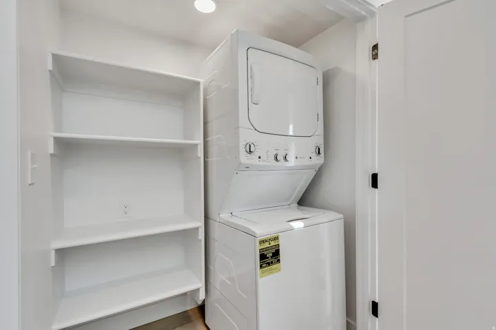 Stackable washer and dryer, built-in shelving, recessed lighting, and a flat panel interior door