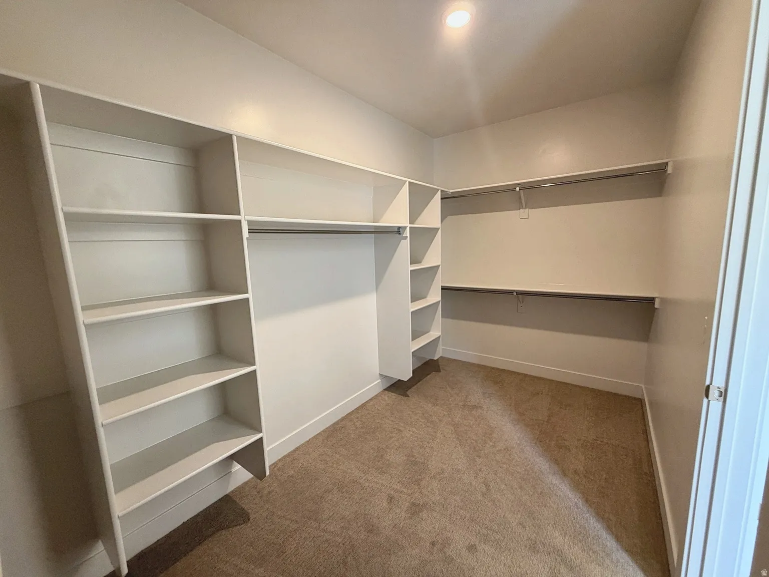 Built-in shelving, hanging rods, recessed lighting, and carpet flooring