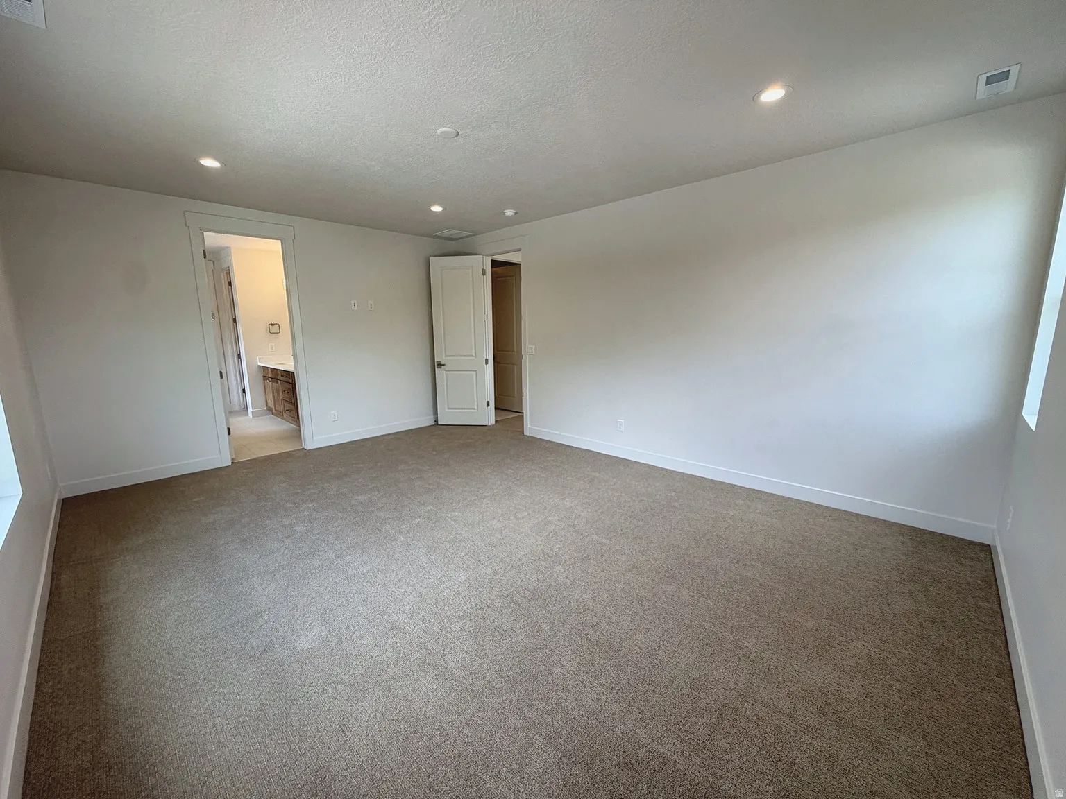 Neutral-toned carpet flooring, recessed ceiling lighting, and white trim