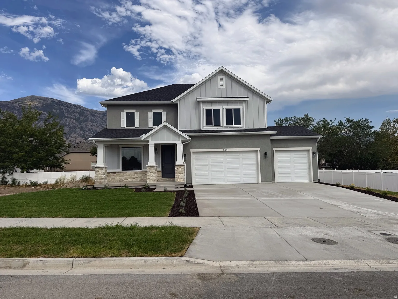 Contemporary exterior with a covered entry, stone accents, two-car garage, and an additional single-car garage