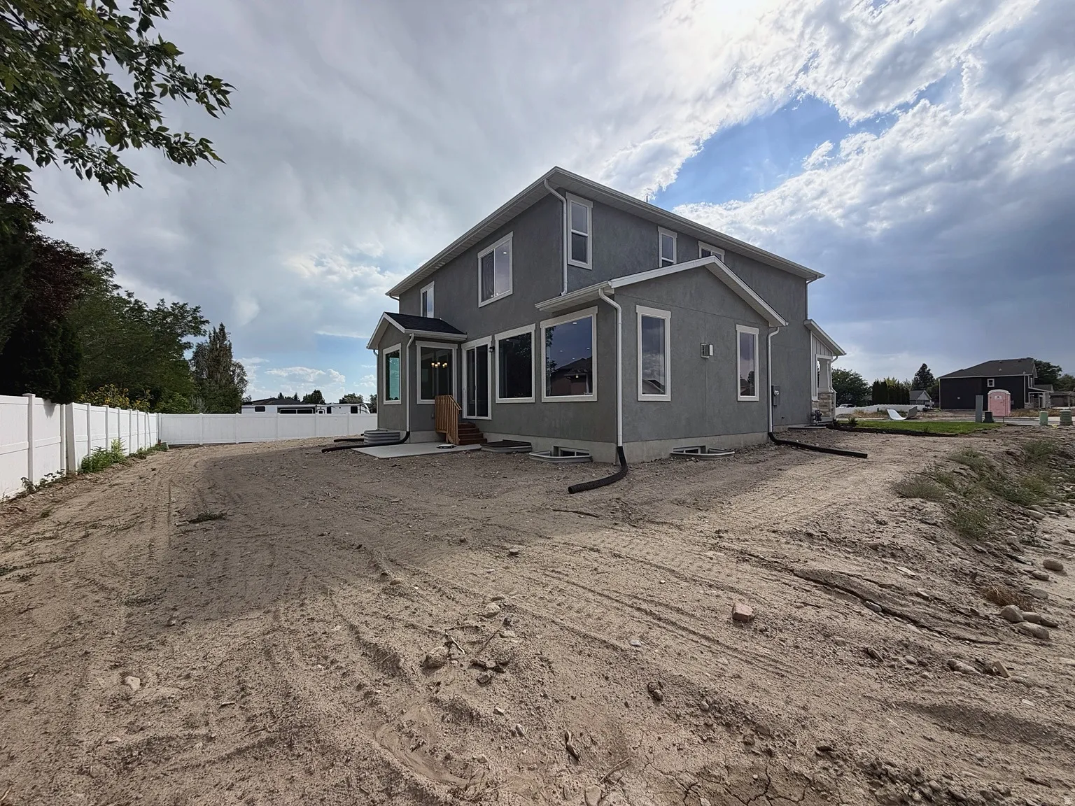 Two-story stucco exterior with white trim, multiple large windows, a bay window feature, and a white privacy fence