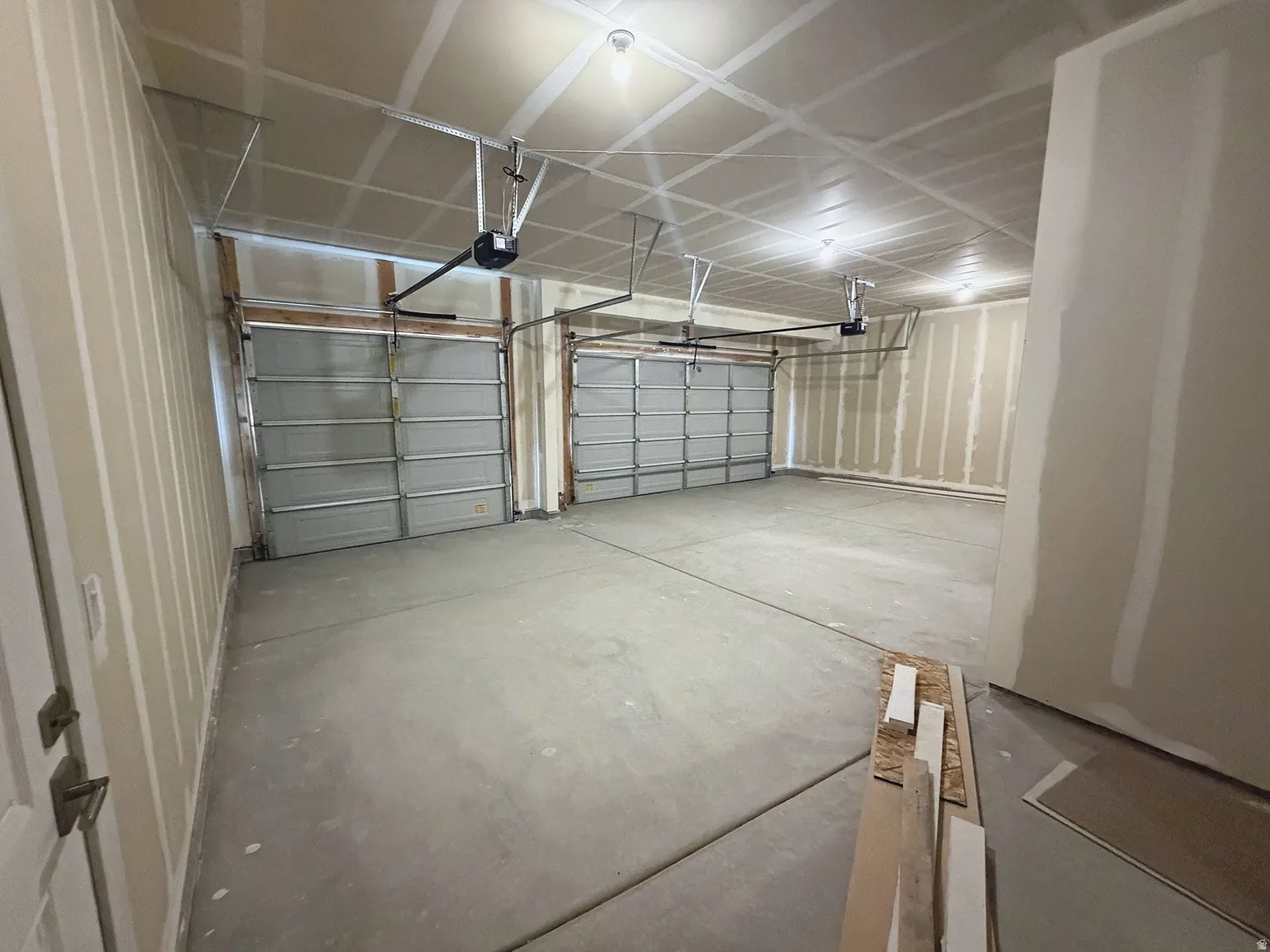 Spacious two-car garage with concrete flooring, two overhead doors, and exposed ceiling joists