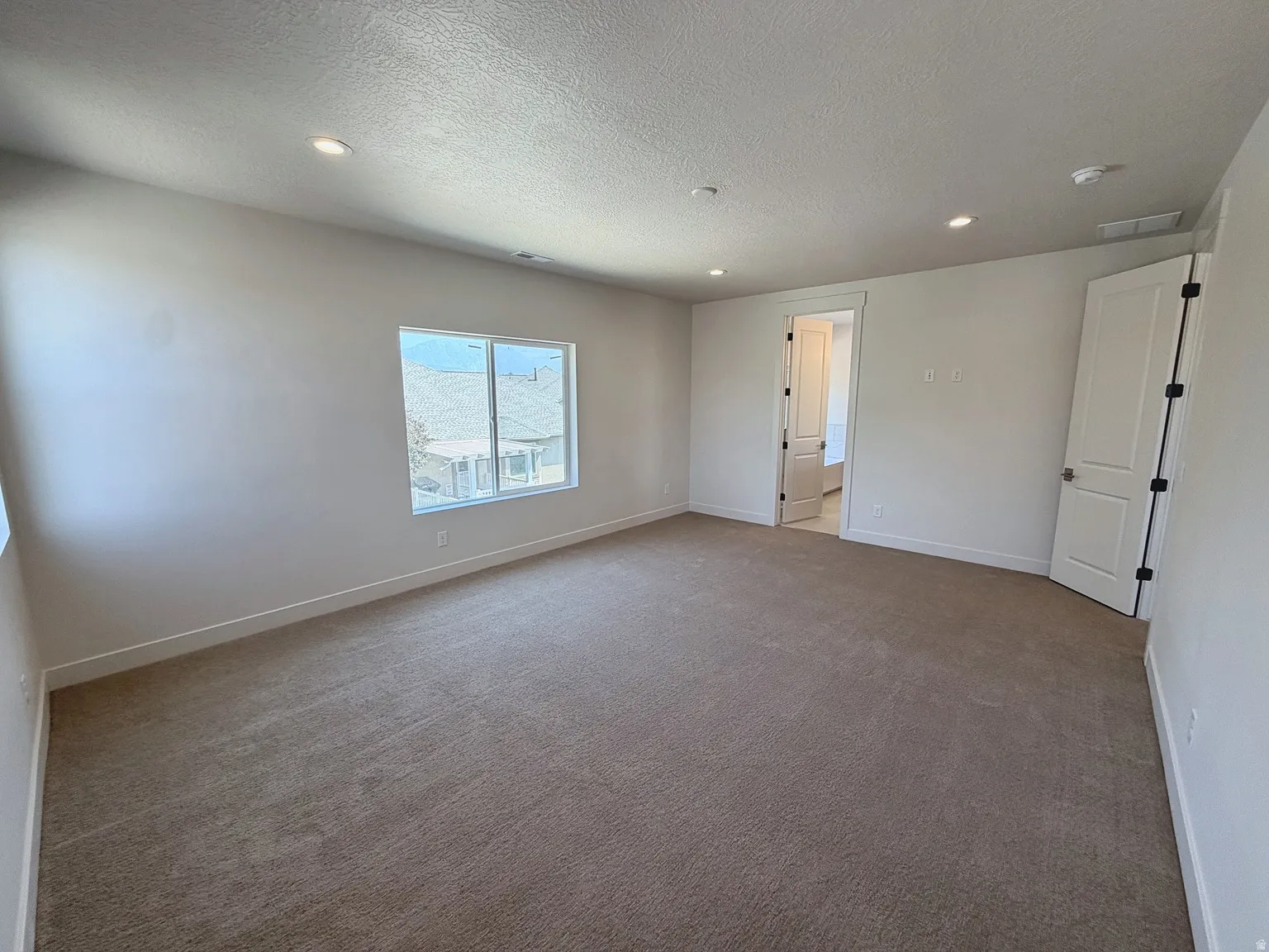 Neutral tone wall paint with recessed lighting, light-colored carpet, and white trim