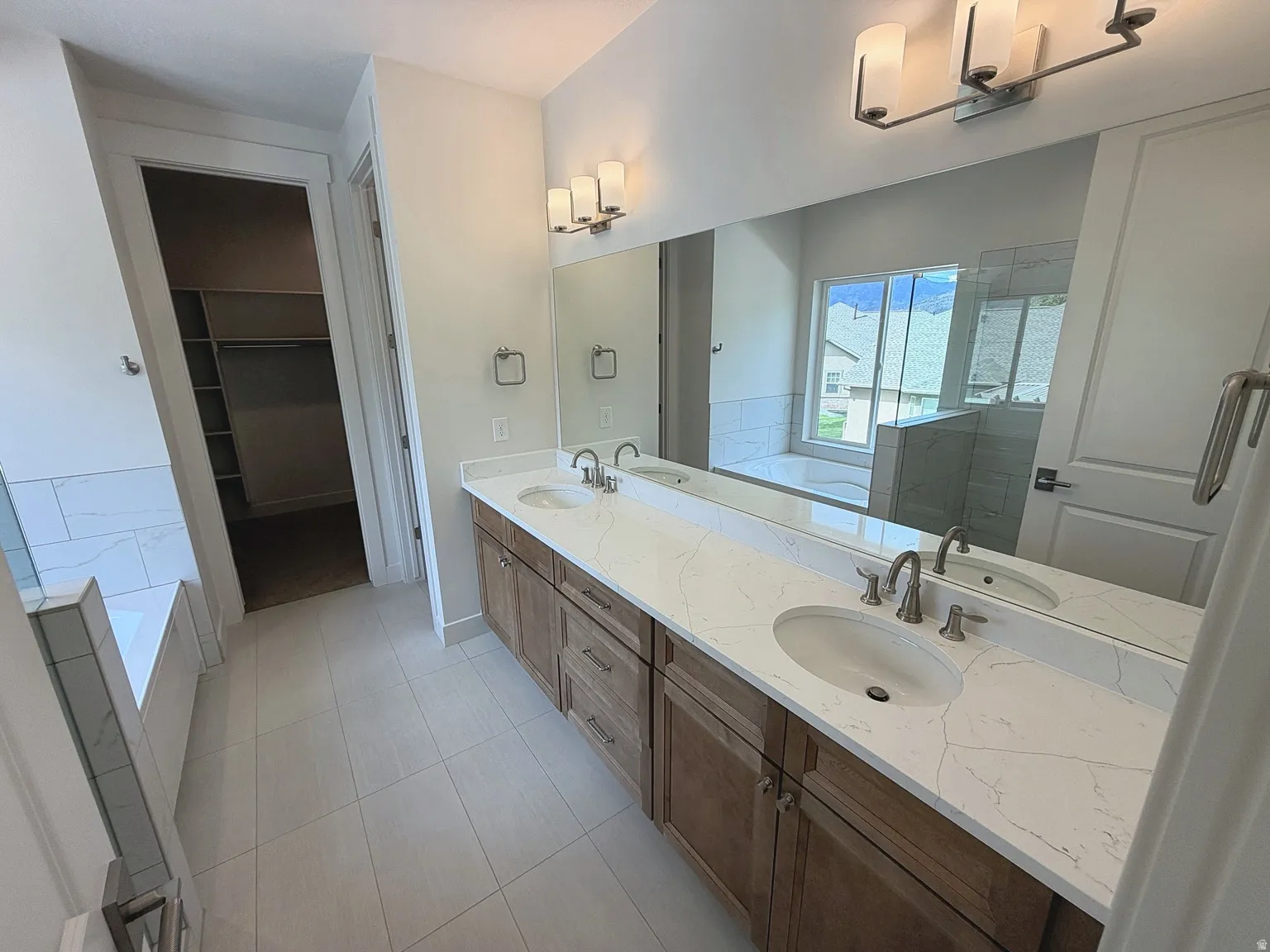 Dual vanity with undermount sinks, wood-finish cabinetry, and a large mirror