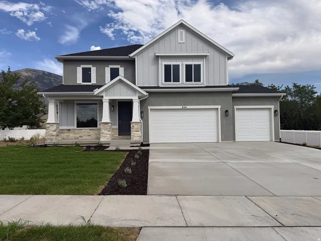 Contemporary two-story exterior with a covered entry, stone column bases, and a multi-car concrete driveway