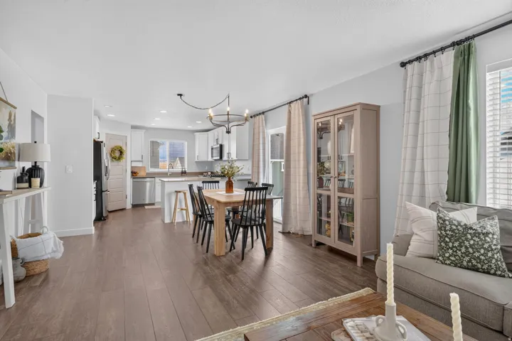 Wood-finish flooring, white cabinetry, stainless steel appliances, and a modern chandelier