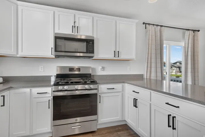 White shaker-style cabinetry with matte black hardware, stainless steel appliances, and solid surface countertops
