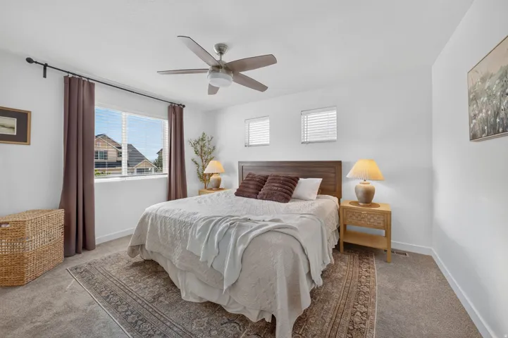 Carpet flooring, multiple windows with blinds, ceiling fan, and a wood-finish headboard