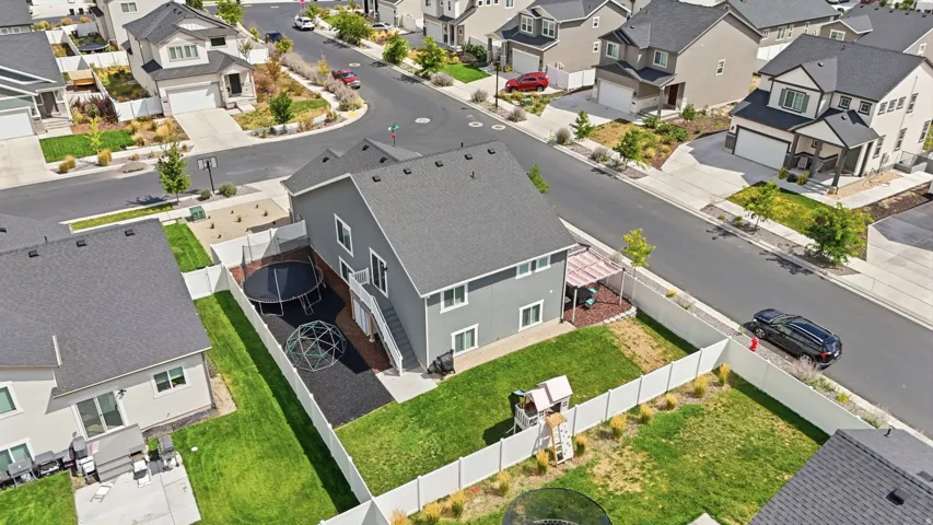 Two-story residence with a dark gray exterior, fenced backyard featuring a grassy area, and an outdoor patio with a pergola