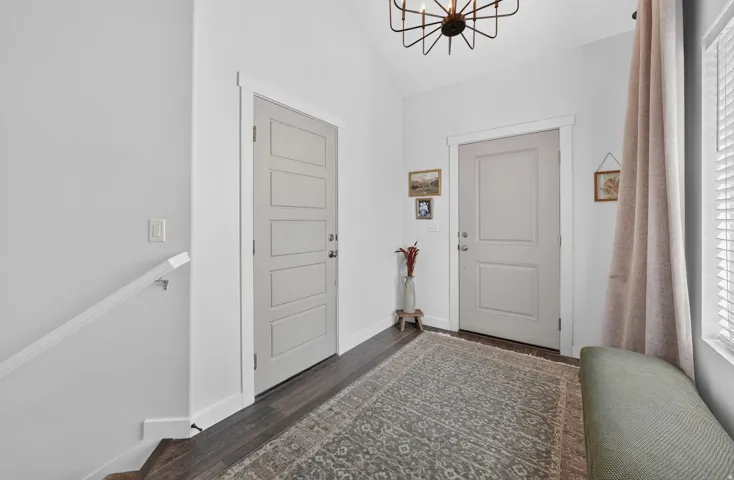 Dark wood-finish flooring with white baseboards, a modern geometric chandelier, and white wall paint