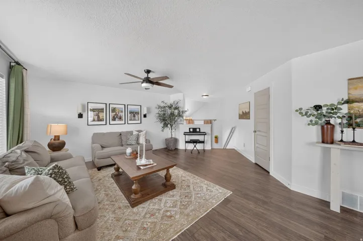 Wood-finish flooring throughout, ceiling fan with integrated lighting, wall sconces, and a paneled interior door