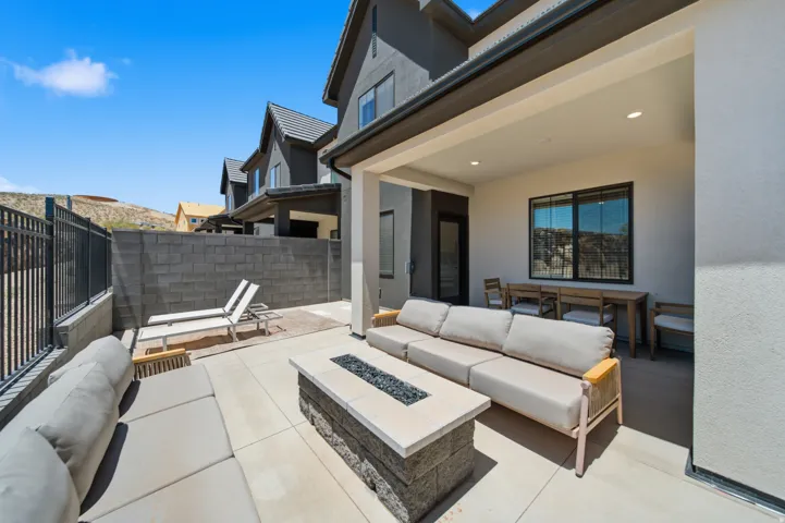 Expansive concrete patio featuring a built-in fire pit, covered outdoor living space with recessed lighting, and a block privacy wall