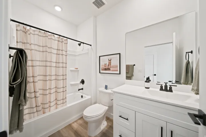 White vanity with a single basin, black fixtures, and a large wall-mounted mirror