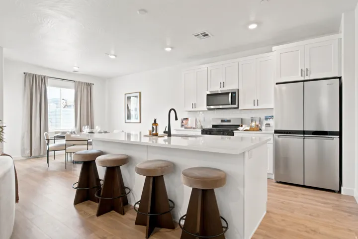 Kitchen featuring an island with countertop seating, white shaker cabinetry, stainless steel appliances, and wood-finish flooring