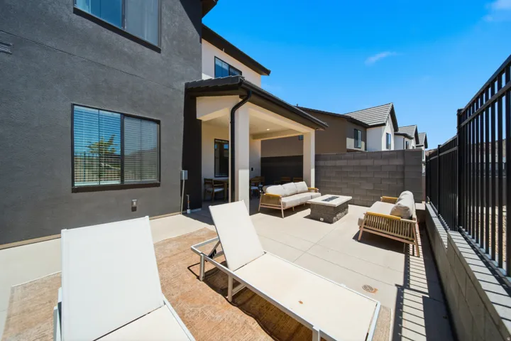 Expansive outdoor patio featuring a covered area, concrete pavers, a privacy wall, and a black perimeter fence
