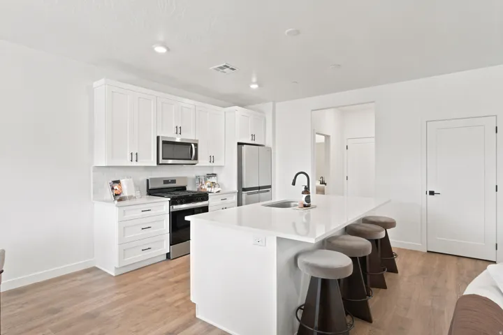 Gourmet kitchen with white shaker cabinetry, stainless steel appliances, white subway tile backsplash, and a large island with a sink and a gooseneck faucet