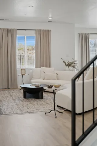Recessed lighting, wood-finish flooring, white walls, and a black metal stair railing