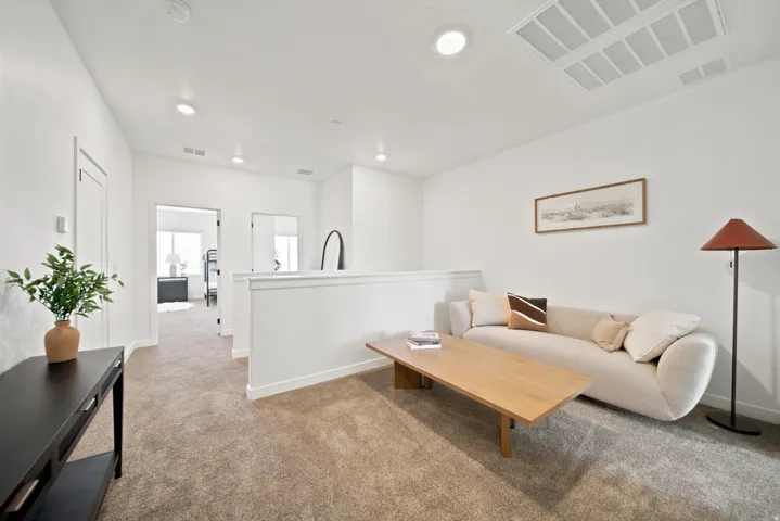 Carpeted flooring throughout, recessed ceiling lighting, crisp white wall finishes, and a white interior railing