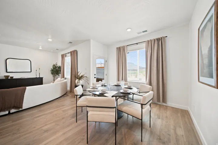 Open-concept living and dining areas featuring light wood-finish flooring, recessed lighting, and bright white walls