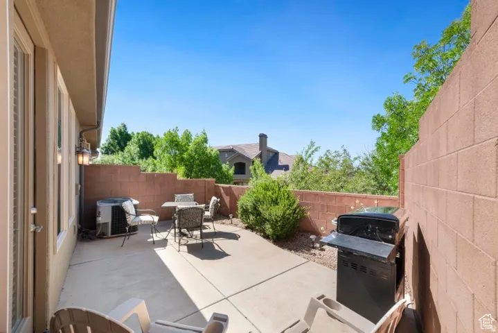Private patio with a concrete surface, bordered by a textured block wall and vibrant green foliage