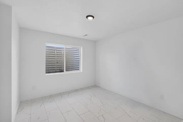 White walls, recessed ceiling lighting, and rectangular floor tiles