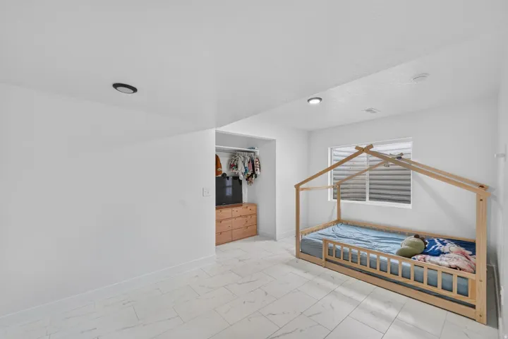 White walls, recessed lighting, and a window with blinds