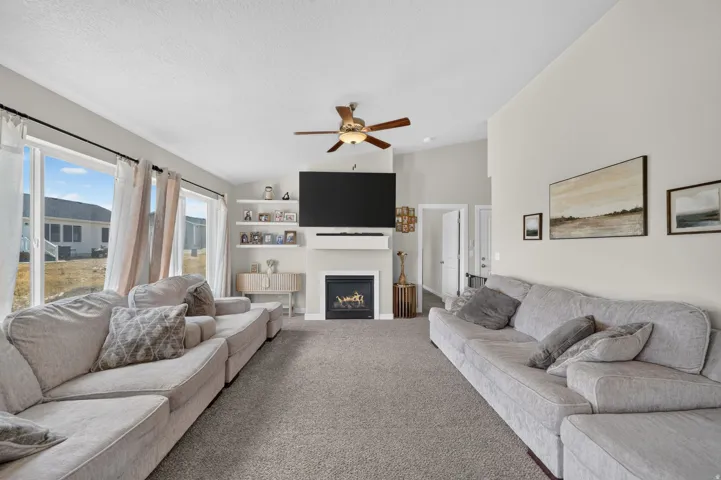 Spacious living area featuring a built-in fireplace, vaulted ceiling, ceiling fan, and large windows