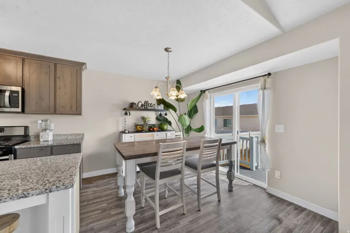 Kitchen dining area with wood-finish flooring, light grey walls, and a glass sliding door
