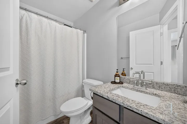 Vanity with a granite-style countertop, undermount sink, and chrome-finish faucet
