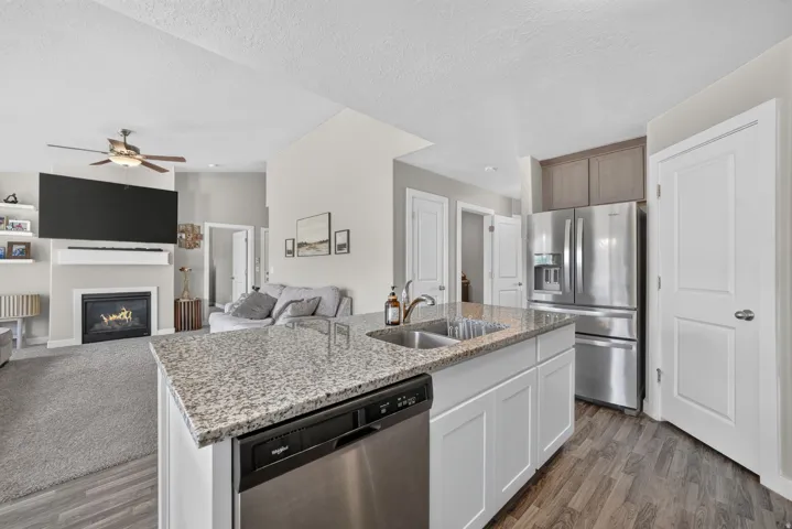 Kitchen island with granite countertop, stainless steel double basin sink, and integrated dishwasher