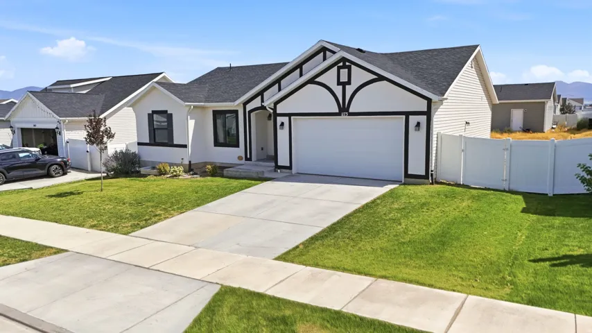 Crafted exterior with black trim details, attached garage, concrete driveway, and a fenced side yard