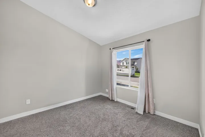 Recessed ceiling light fixture, neutral wall paint, carpet flooring, and a double-pane window