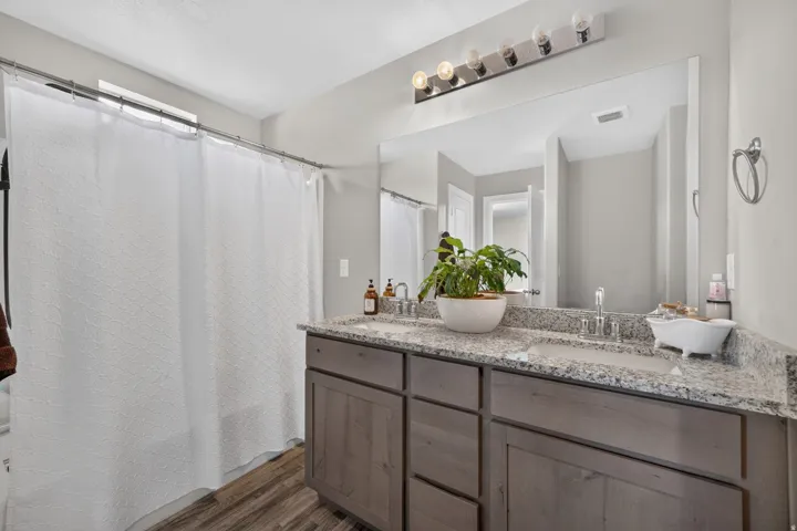 Dual vanity with granite-style countertop, wood-finish cabinetry, and undermount sinks