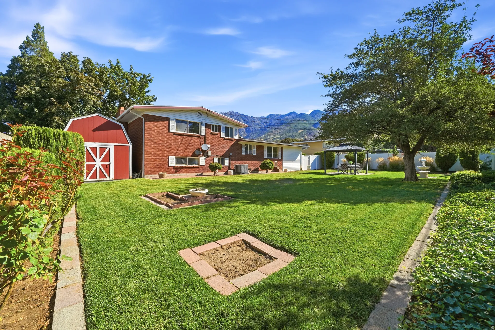 Expansive backyard with a lush lawn, brick-clad home, and a red barn-style shed