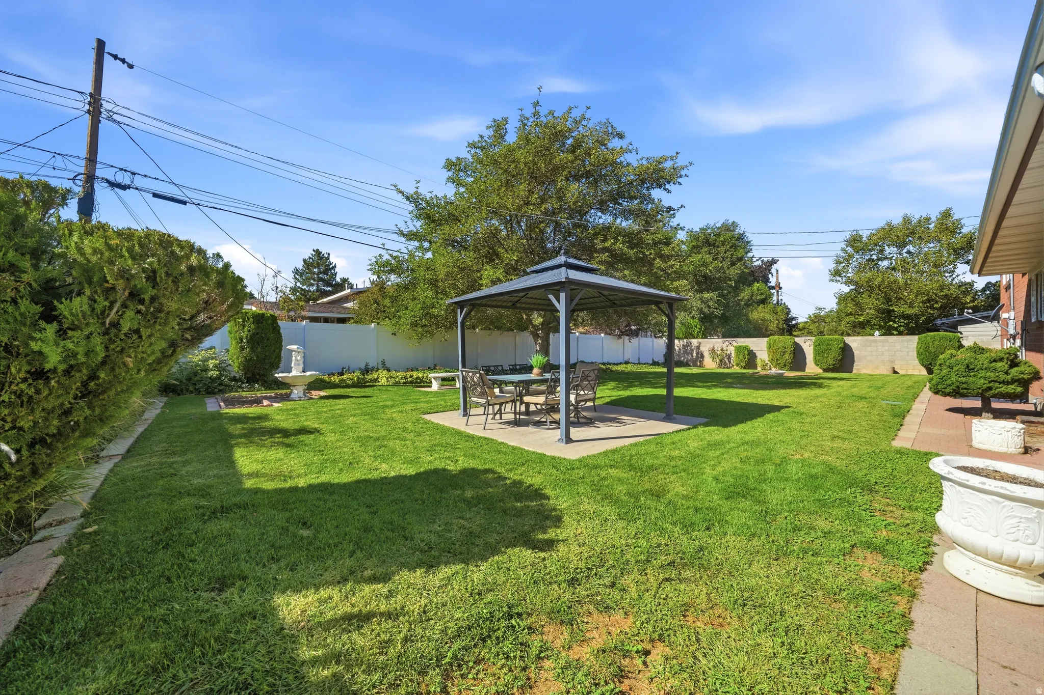 Expansive backyard featuring a central lawn, covered patio area, and mature perimeter landscaping