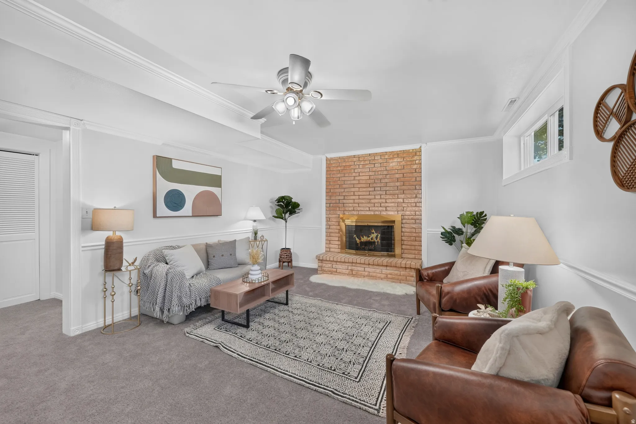 Spacious living area featuring a brick fireplace, ceiling fan with integrated lighting, and crown molding