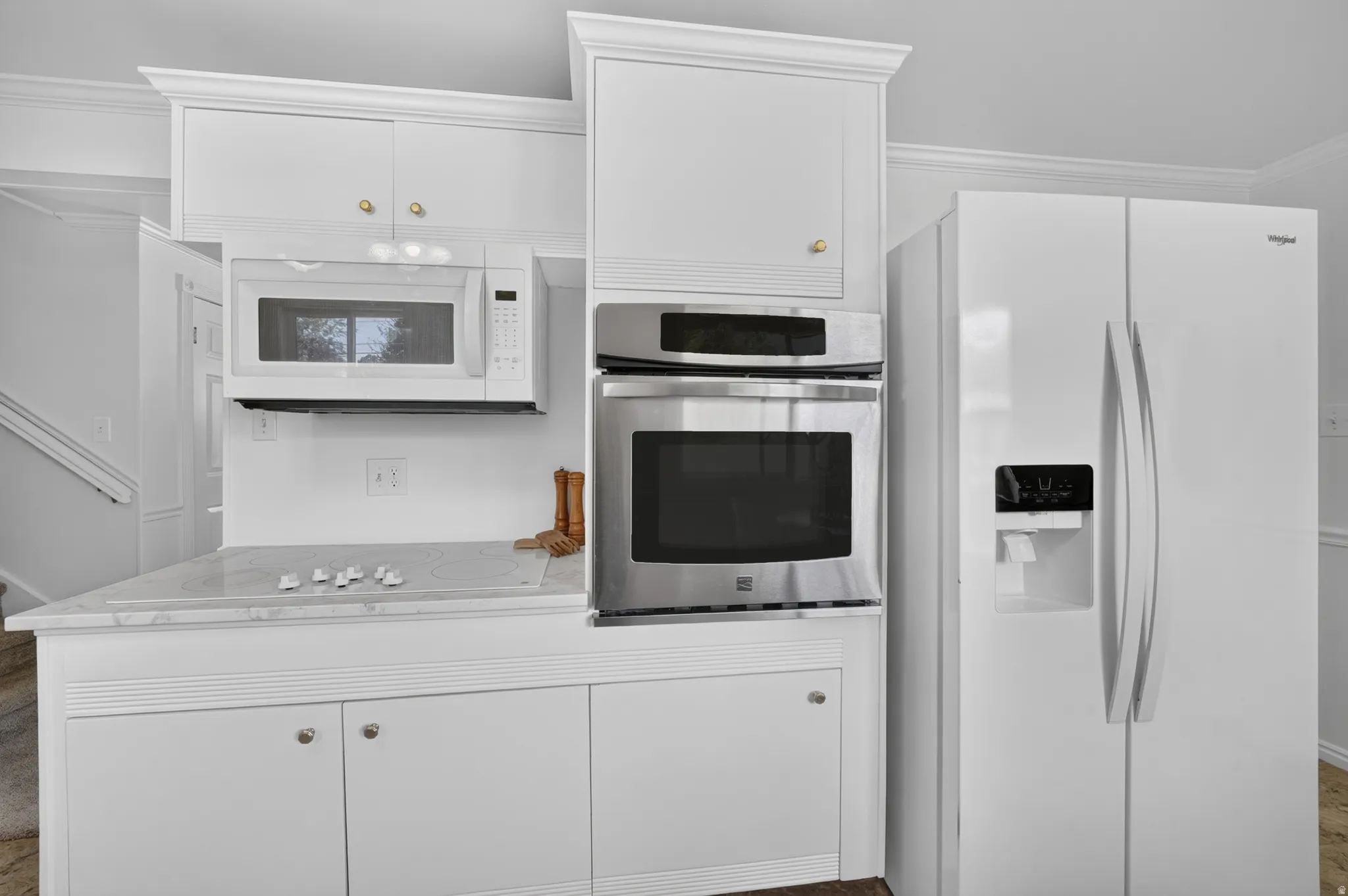 White cabinetry with crown molding, stainless steel built-in oven, built-in microwave, and a smooth cooktop
