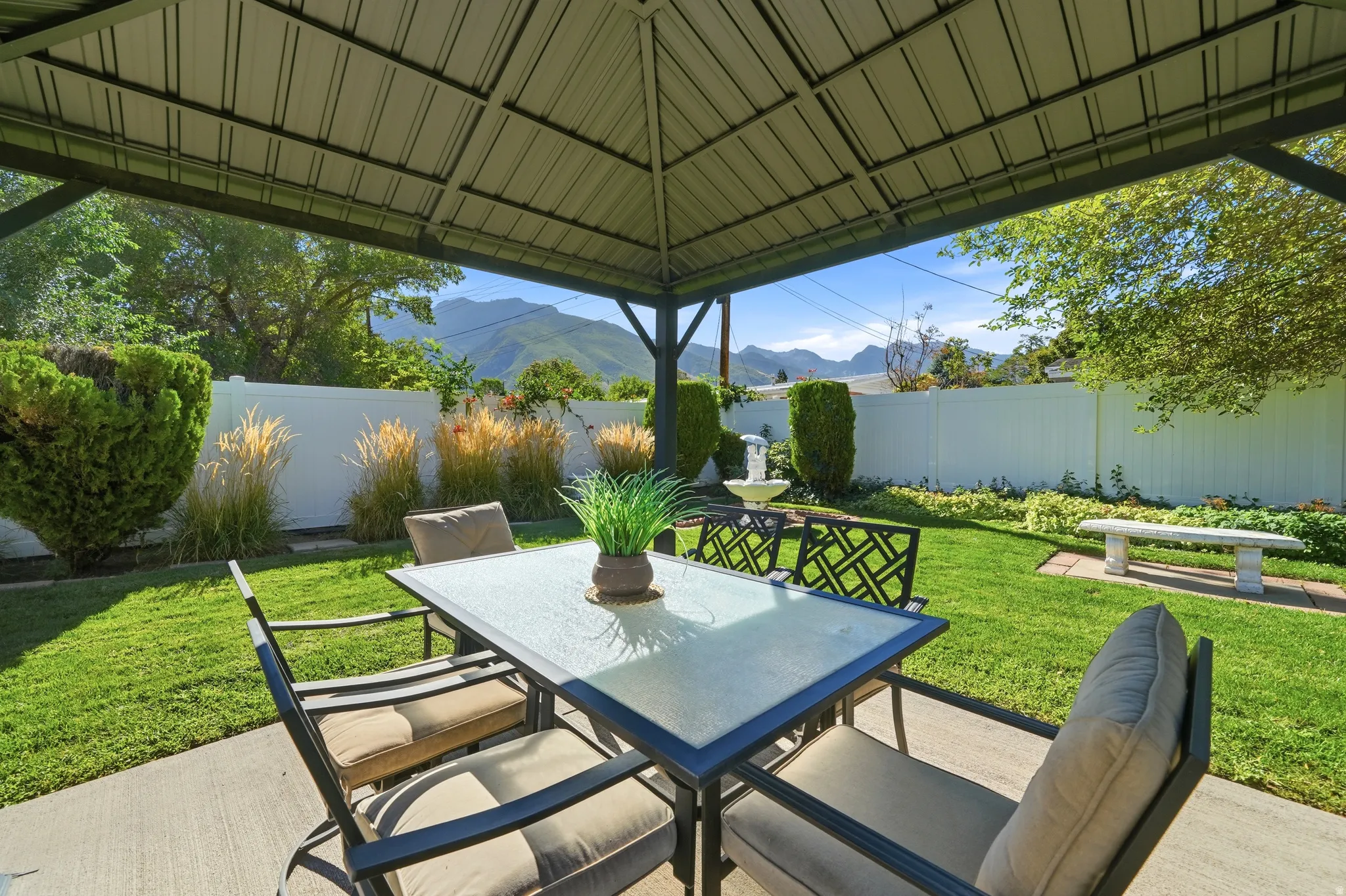 Paved patio with covered gazebo, grassy yard, and white privacy fence
