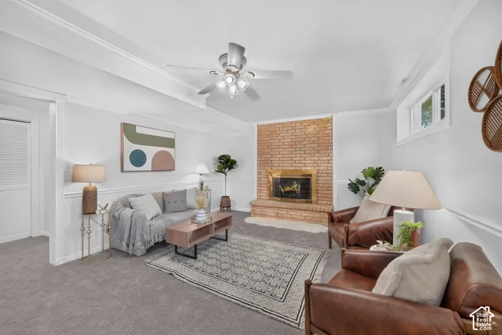 Spacious living area featuring a brick fireplace, ceiling fan with integrated lighting, and crown molding