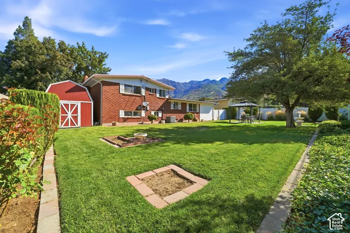 Expansive backyard with a lush lawn, brick-clad home, and a red barn-style shed