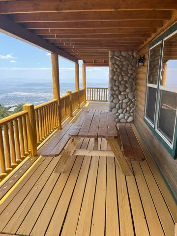 Expansive wood-plank deck with a log railing, offering a panoramic mountain backdrop