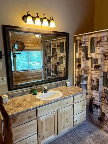 Vanity with a laminate countertop and an integrated sink, framed mirror, and a four-light fixture