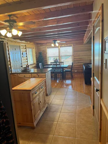 Exposed wood beam ceiling, wood-paneled walls, wood-finish flooring, tile flooring, and built-in cabinetry