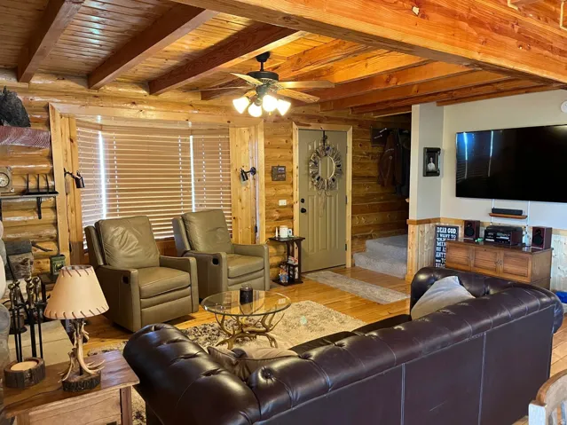 Living area featuring wood-paneled walls and ceiling with exposed beams