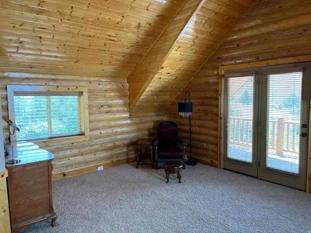 Wood-paneled walls and ceiling, wall-mounted window, and double glass doors opening to an exterior balcony