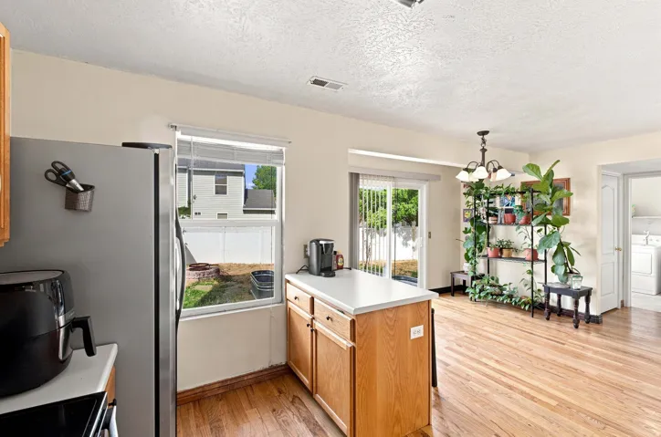 Hardwood flooring, sliding glass door, white kitchen island with cabinetry, stainless steel refrigerator, and recessed lighting